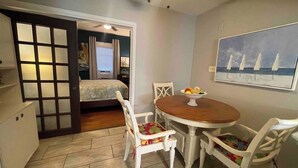 Une pièce de taille modeste comprenant un lit, une table à manger avec des chaises, un petit coin cuisine et un tableau accroché au mur.