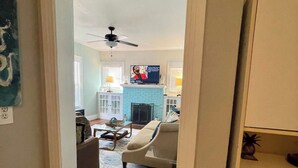 Un salon avec une cheminée, un téléviseur et un ventilateur de plafond.