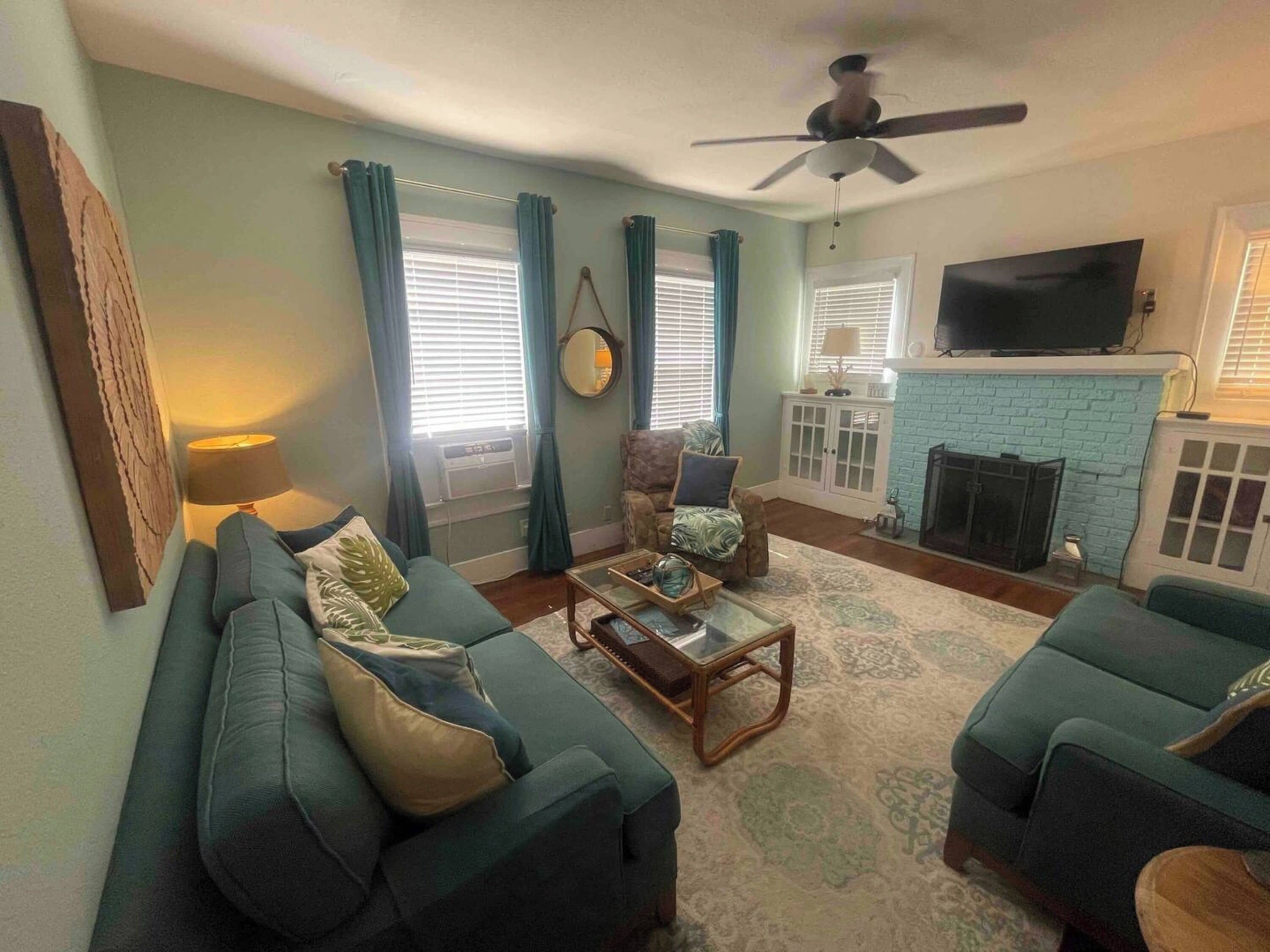 A living room with two green sofas, a coffee table, a TV, and a fireplace.