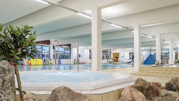 An indoor swimming pool with a hot tub, surrounded by rocks and a potted plant. - "Alvira" - 30km from the sea by Interhome (Toftlund)