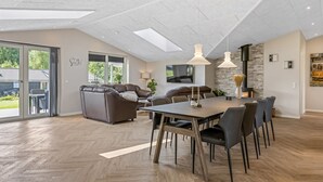A spacious room with a large dining table, comfortable seating, a fireplace, and a view of the outdoors. - "Alvira" - 30km from the sea by Interhome (Toftlund)