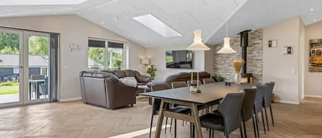 A spacious room with a large dining table, comfortable seating, a fireplace, and a view of the outdoors.