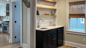 A modern kitchen with black cabinets, a white countertop, and a window with blinds.