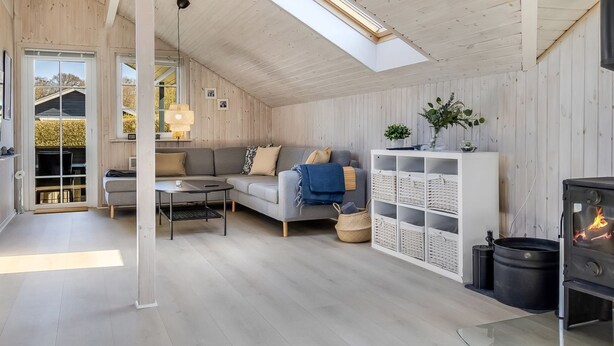 A spacious loft with a high ceiling, a skylight, a cozy living area with a sofa and coffee table, a white shelving unit, and a wood-burning stove. - "Aika" - 450m from the sea by Interhome (Hejls)