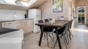 A modern kitchen with skylights, a dining area with a table and chairs, and a wooden interior. - "Aika" - 450m from the sea by Interhome (Hejls)