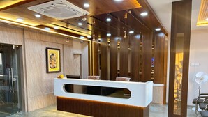 A reception area with a modern design, featuring a white reception desk, wooden accents, and a marble floor. - HOTEL SHREE HARI (Dwarka)