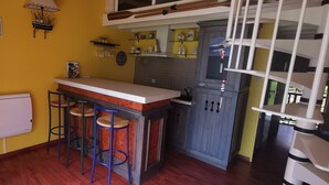 A compact kitchen with a bar area, stools, and a small refrigerator.
