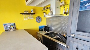 A kitchen with a yellow wall, wooden cabinets, and a white countertop.