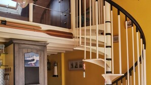A kitchen with a wooden ceiling, a white spiral staircase, and a dining area with a table and chairs.