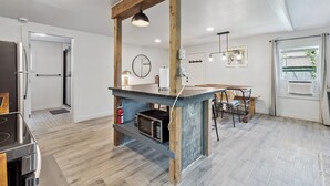 Una cocina moderna con una isla de madera, horno microondas integrado e iluminación colgante.