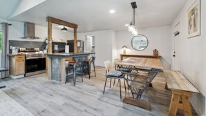 Una cocina moderna con una isla central, taburetes de bar y una mesa de comedor con bancos.