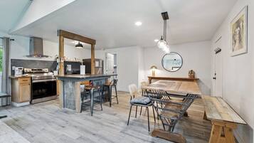 Une cuisine moderne dotée d’un îlot central, de tabourets de bar et d’une table à manger avec des bancs.