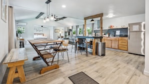 Una cocina moderna con piso de madera, una isla central y un refrigerador de acero inoxidable.