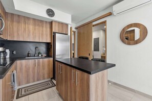 A modern kitchen with wooden cabinets, a black countertop, and a built-in refrigerator.