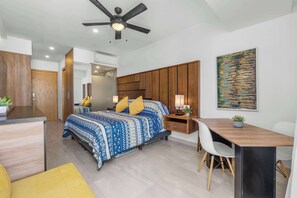 A modern bedroom with a bed, bedside tables, a desk, and a ceiling fan.