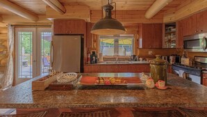 Eine Küche mit Granit-Arbeitsplatten, Holzschränken und einer großen Hängeleuchte.