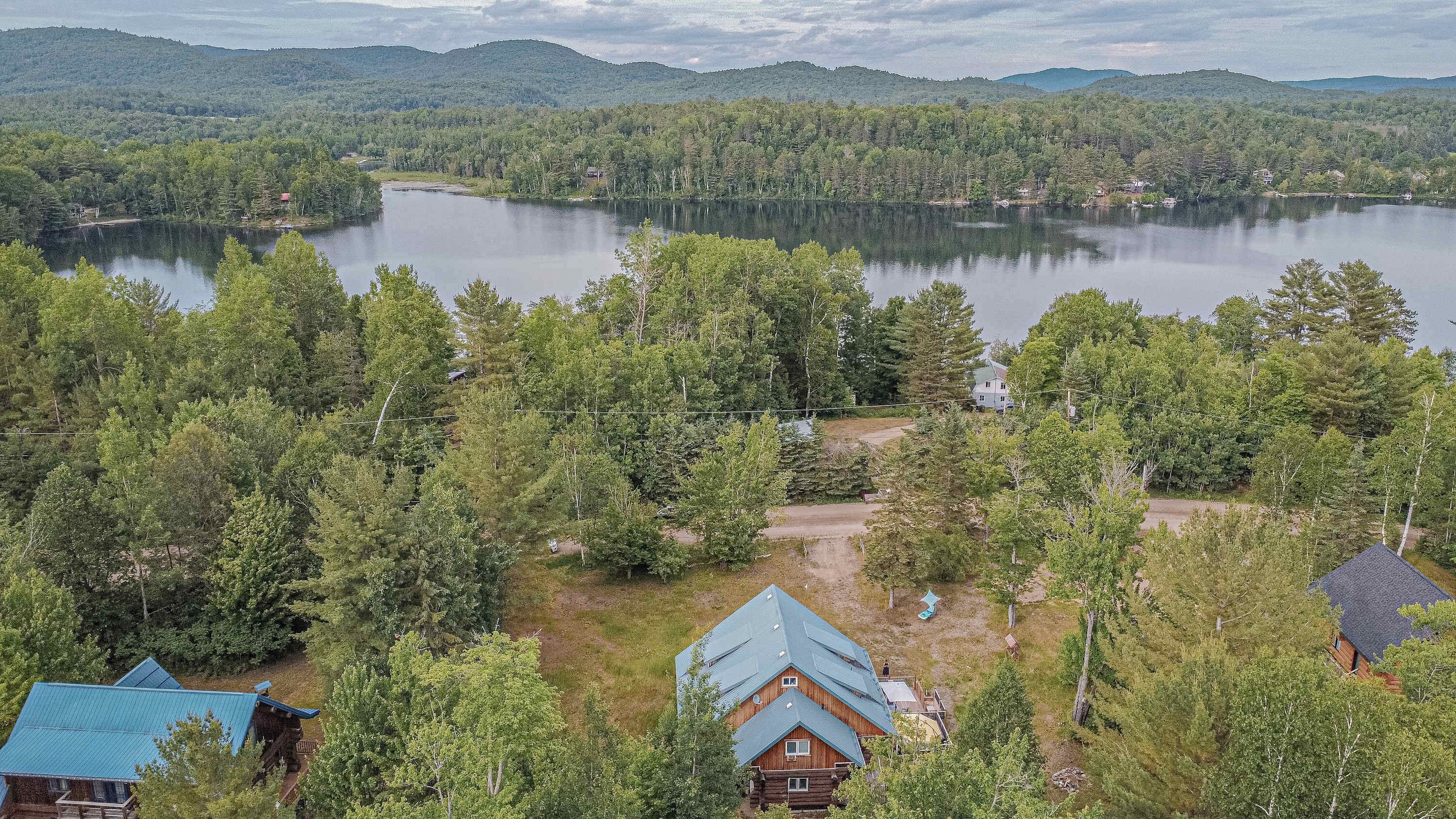 Cabin nestled in trees with lake and rolling hills in the distance