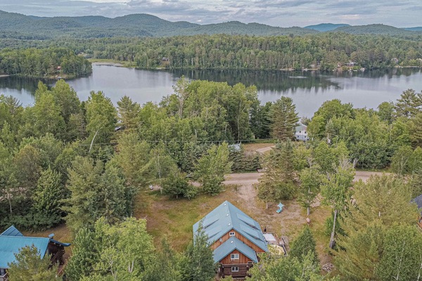 Cabin nestled in trees with lake and rolling hills in the distance