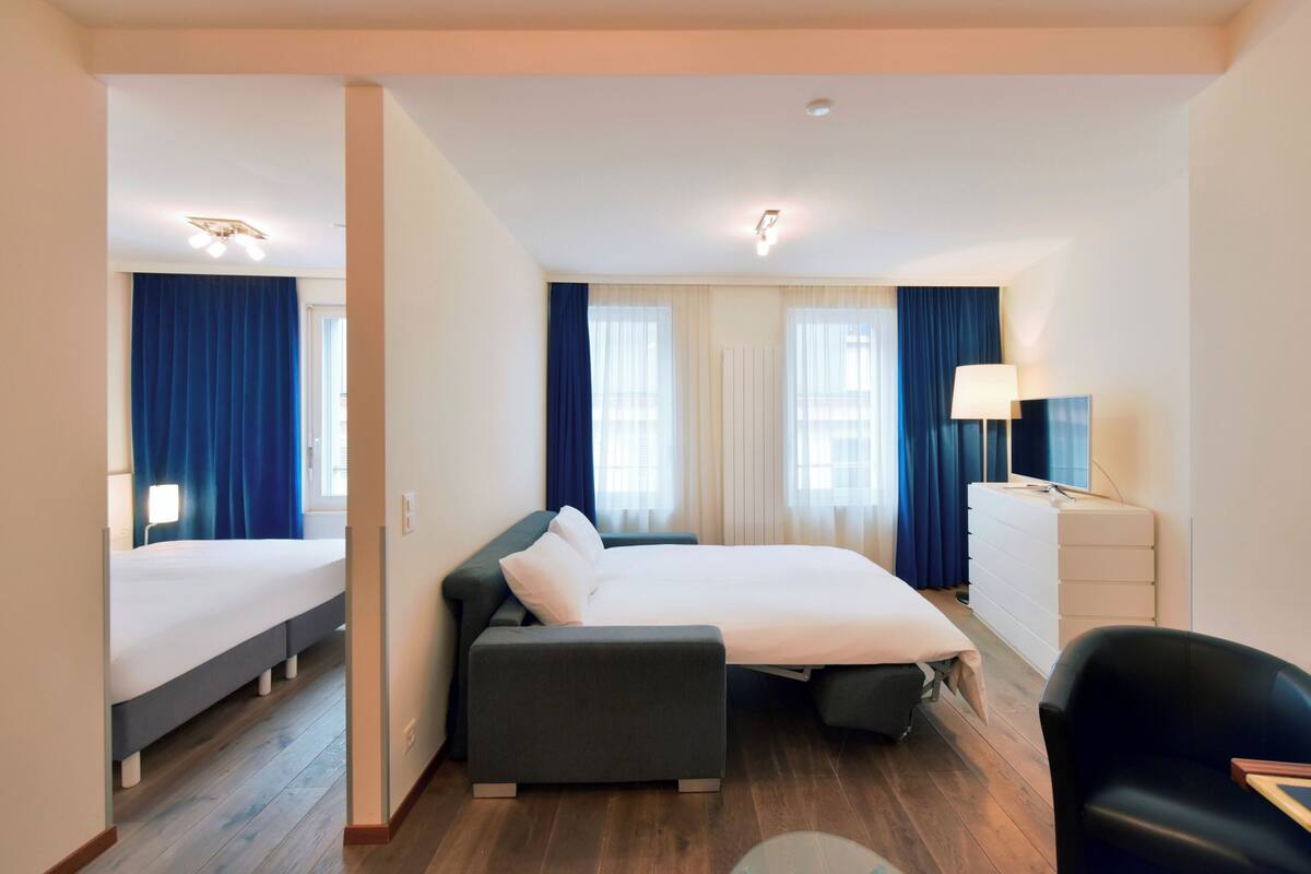 Una habitación de hotel con una cama grande, un sofá, un escritorio y una silla.