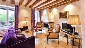 A cozy living room with a sofa, chairs, a fireplace, and a television. - Rouvenaz Appartements (Montreux)