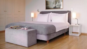 A bedroom with a bed, bedside lamps, a nightstand, a wardrobe, and a painting on the wall. - Rouvenaz Appartements (Montreux)