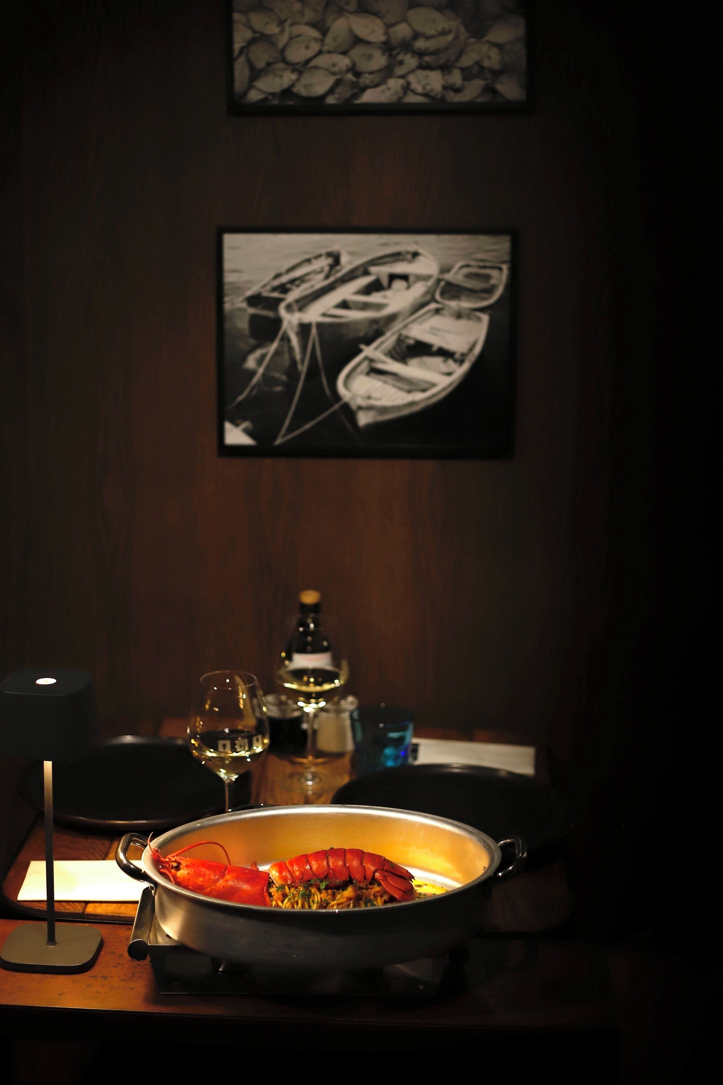 A dining table with a lobster dish, wine glasses, and a candle.