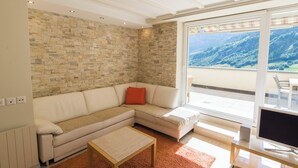 A modern living room with a sectional sofa, a coffee table, and a TV on a stand. - The Cristal apartment house is situated in a quiet, sunny and central location (Leukerbad)