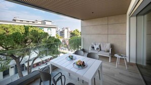 Un balcón moderno con techo de madera, una mesa de comedor con sillas y un sofá.