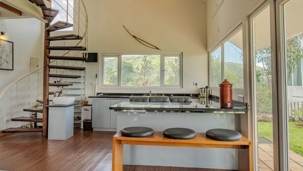Une cuisine moderne dotée d’un îlot central, d’un escalier en colimaçon et de grandes fenêtres.