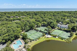 A large estate with multiple tennis courts, a swimming pool, and a lake.