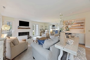 A spacious living room with a sofa, coffee table, and a TV mounted on the wall.