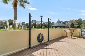 A wooden deck with a pergola, outdoor seating, and a lamp post.