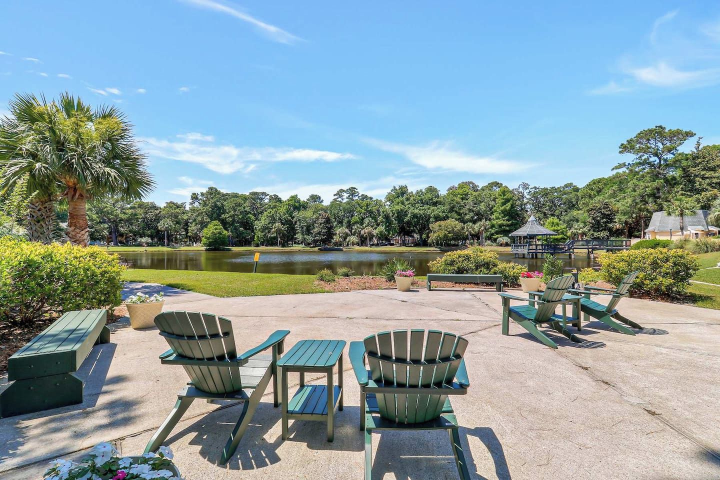 An outdoor seating area with chairs and tables, a palm tree, and a lake view.