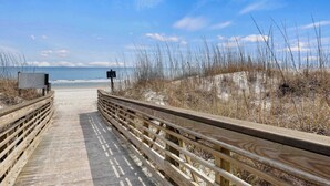 A wooden boardwalk leading to a beach with a clear sky.