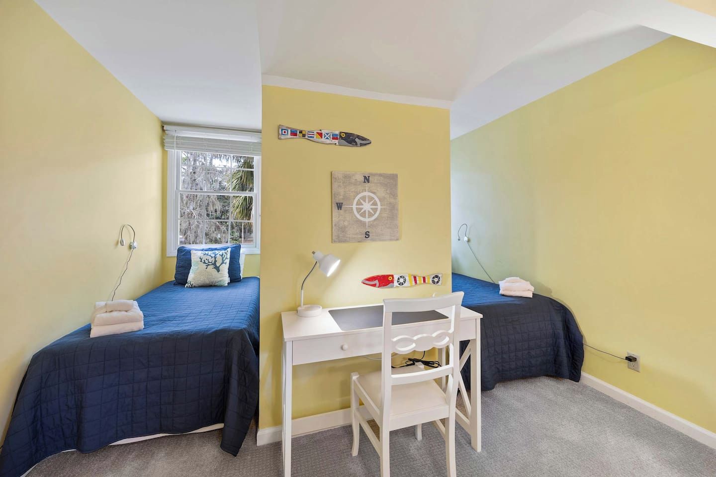 Une chambre avec deux lits, un bureau et une fenêtre.