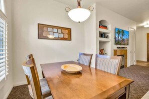 Spiseområde med et træbord, stribede stole og en dekorativ lampe.