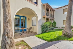 A two-story building with a covered patio, outdoor seating, and a well-maintained garden.