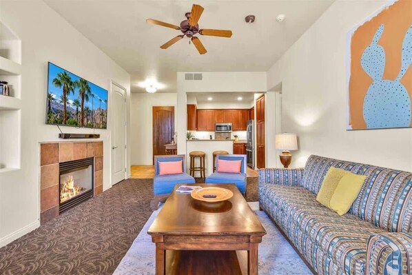 A living room with a fireplace, a ceiling fan, a sofa, a coffee table, and a television.
