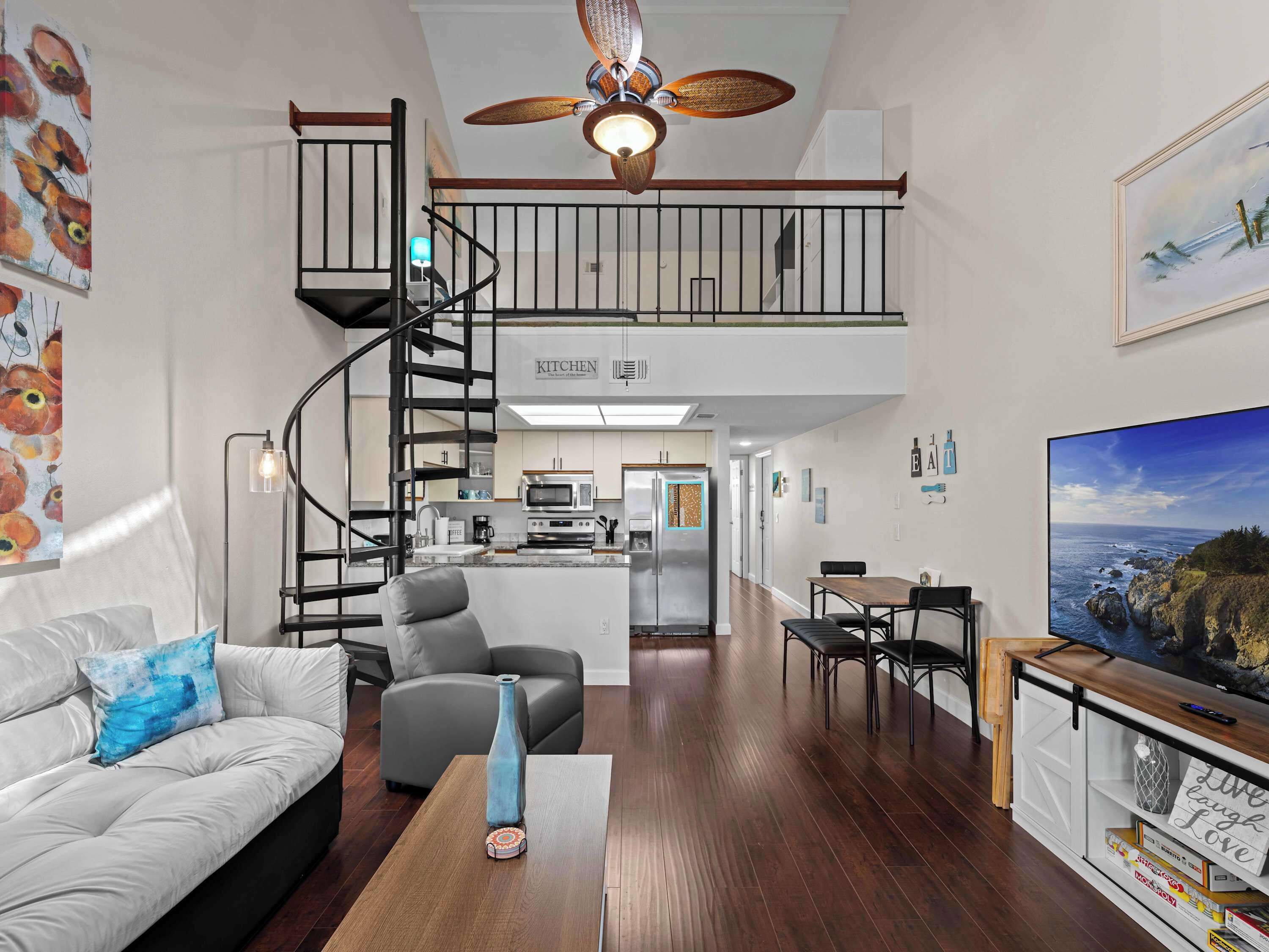 A spacious living area with a staircase leading to an upper level, a kitchen, and a dining area.