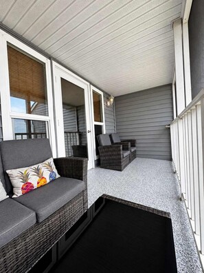 A covered outdoor seating area with wicker furniture and a patterned rug.