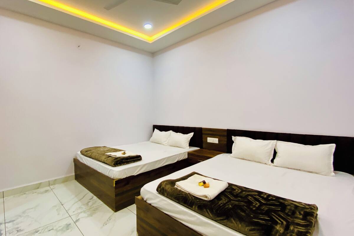A hotel room with two beds, a wooden wardrobe, and a ceiling light fixture.