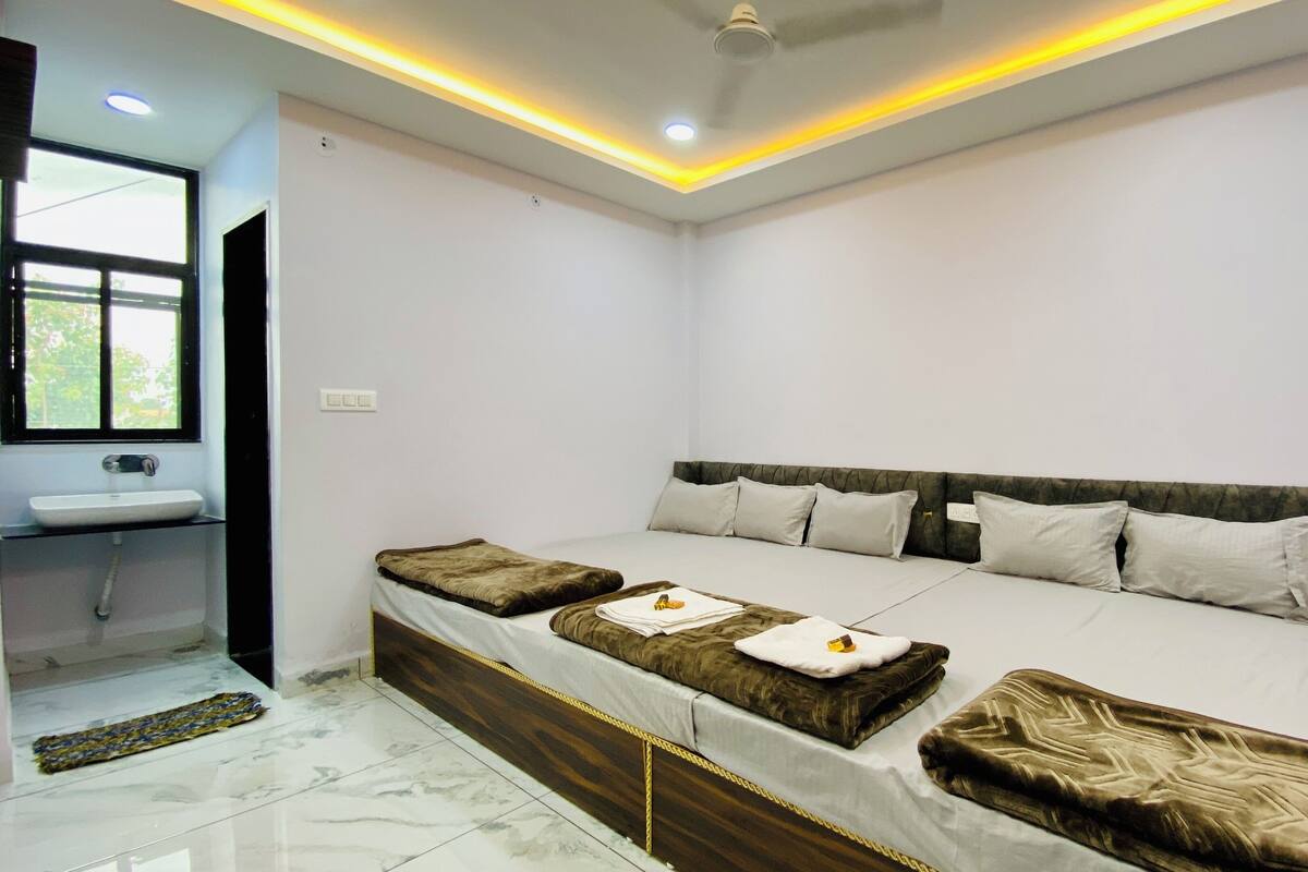 A modern hotel room with a large bed, a bedside table, a window, and a bathroom.