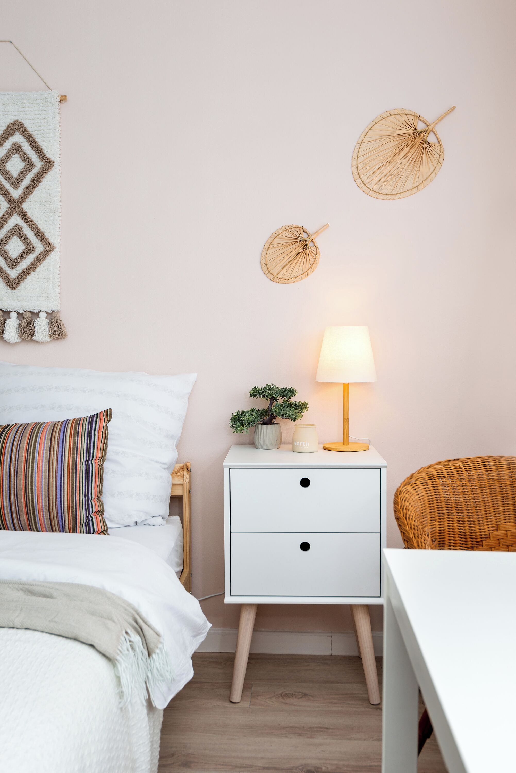 A neatly arranged bedroom with a bed, bedside table, lamp, and decorative items.