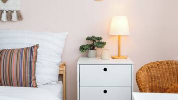 A neatly arranged bedroom with a bed, bedside table, lamp, and decorative items.