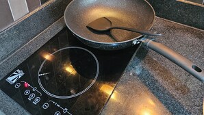 A kitchen with a black induction cooktop and a frying pan on it. - Cozy studio condo with WiFi, AC in beautiful Makati (Makati)