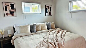 A bedroom with a bed, bedside tables, and artwork on the walls.