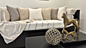 A modern living room with a sofa, decorative items, and abstract wall art. - Sleek+Serene ADU | Modern Kitchen • Outdoor Vibes (Carmichael)