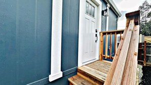 A house with a blue exterior, a white door, and a wooden staircase leading to a porch. - Sleek+Serene ADU | Modern Kitchen • Outdoor Vibes (Carmichael)