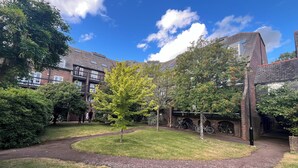 A courtyard with a central lawn, brick buildings, and bicycles parked against the walls.