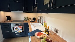 A modern kitchen with dark cabinets, a wooden countertop, and a dining area set with plates, cutlery, and a bottle of wine.